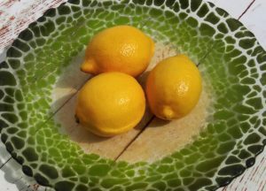 Lemons arranged in large green crackle glass dish