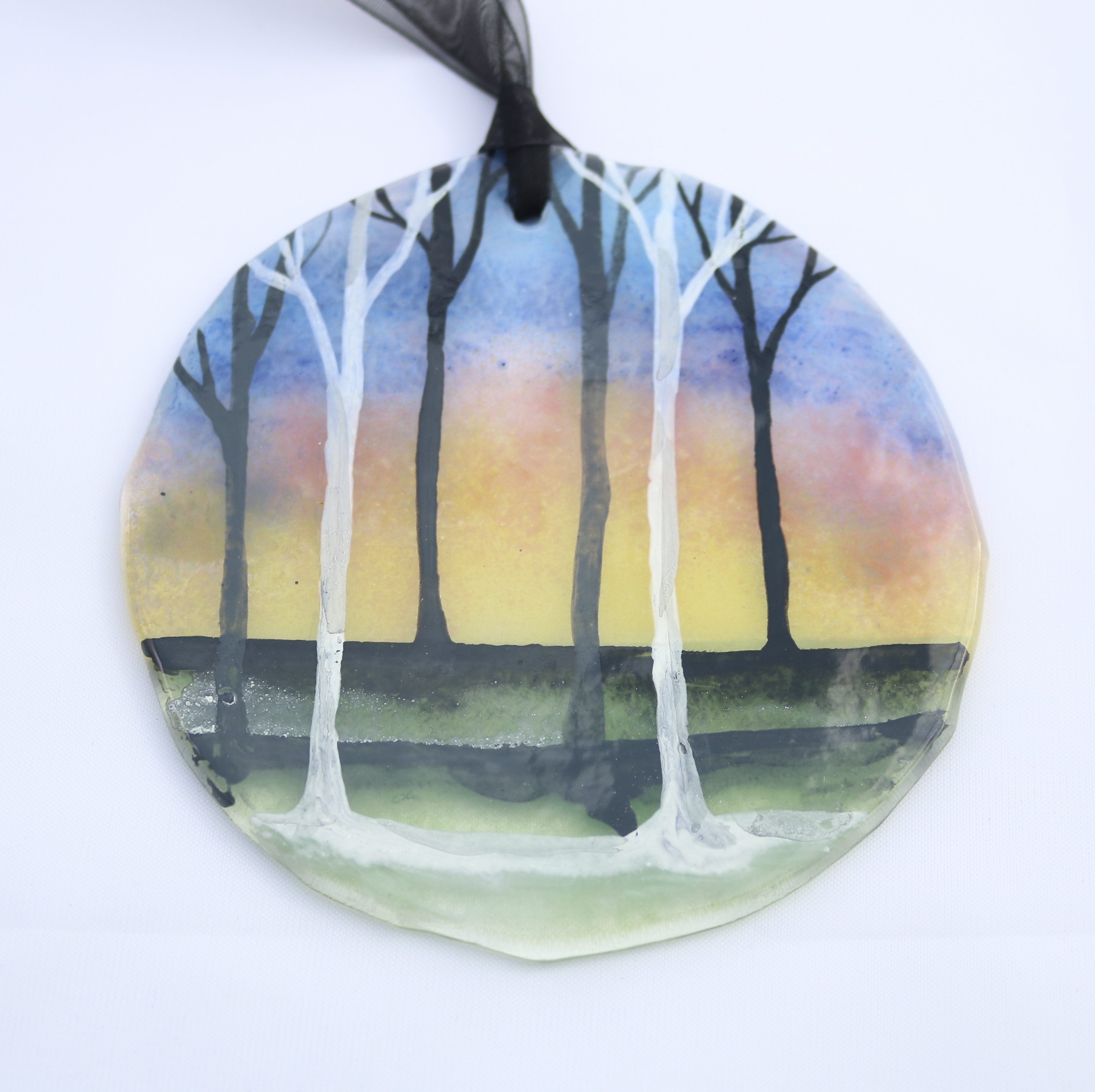 Multicoloured sunrise with tree silhouettes on fused glass
