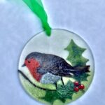 Close-up image of robin suncatcher, with a robin standing on holly branch with berries